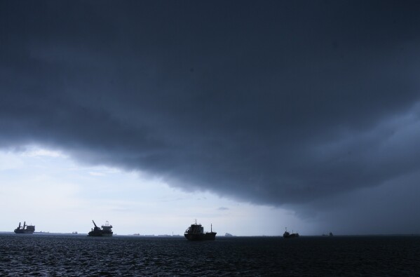 FILE - Storm clouds gather overhead as cargo ships that wait to move through the Panama Canal are anchored on the Atlantic side of the Panama Canal, seen from Colon, Panama, Sept. 4, 2023. The climate phenomenon known as El Niño — and not climate change — was a key factor driving low rainfall that disrupted shipping at the Panama Canal, scientists said Wednesday, May 1, 2024. (AP Photo/Arnulfo Franco, File)