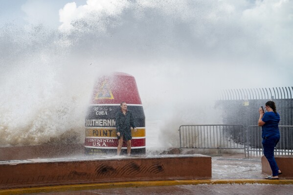 Visitors to the Southernmost Point buoy brave the waves made stronger from Hurricane Idalia on Tuesday, Aug. 29, 2023, in Key West, Fla. Feeding on some of the hottest water on the planet, Hurricane Idalia is expected to rapidly strengthen as it bears down on Florida and the rest of the Gulf Coast, scientists said. (Rob O'Neal/The Key West Citizen via AP)