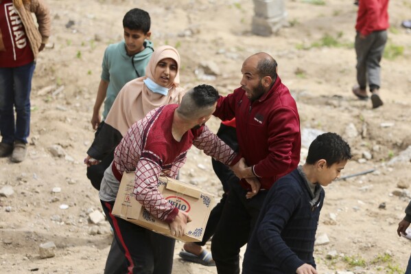 Palestinians rush to collect the humanitarian aid airdropped into Gaza City, Gaza Strip, on Sunday, March 17, 2024. (AP Photo/Mohammed Hajjar)