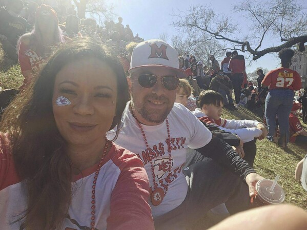 In this photo provided by Casey Filter, Casey and her husband, Trey Filter, on Wednesday, Feb. 14, 2024, in Kansas City, Mo.  Attending Kansas City Chiefs festivities with his 12 and 15-year-old sons.  The family was walking to their car when they heard gunshots and someone screaming. "Meet him!" Trey encounters a man fleeing with a firearm, who falls to the ground before being secured by Casey until the police arrive.  (KC Filter via AP)
