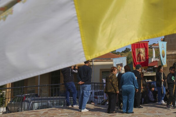 A Vatican flag waves as the worshippers follow a traditional procession on the Feast Day of St. George outside St. George Church in the Maronite village of Kormakitis in the breakaway north of the ethnically divided Cyprus on Wednesday, April 23, 2025. (AP Photo/Petros Karadjias)