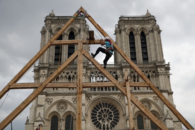 FILE - Charles, one of the carpenters, shows off the skills of his medieval colleagues in the square in front of the Notre Dame Cathedral in Paris, France, Saturday, Sept. 19, 2020. The restoration of Notre Dame reaches a milestone on Friday the 19th December 2020. January 8, 2023: one year until the cathedral reopens its enormous doors to the public.  (AP Photo/François Mori, File)