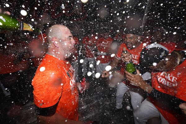 Baltimore Orioles manager Brandon Hyde, left, reacts with his team during a locker room celebration after the Orioles defeated the Tampa Bay Rays 5-4 in 11 innings of a baseball game to clinch a postseason spot, Sunday, Sept. 17, 2023, in Baltimore. (AP Photo/Julio Cortez)
