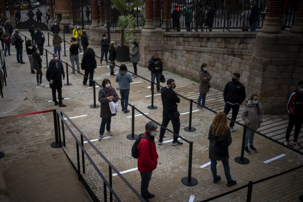 FILE - In this Dec. 1, 2020, file photo, people wait their turn to be called for a PCR test for the COVID-19 outside a hospital in Barcelona, Spain. Scientists say there is reason for concern but not alarm about new strains of the coronavirus, especially the one currently spreading in England. (AP Photo/Emilio Morenatti, File)