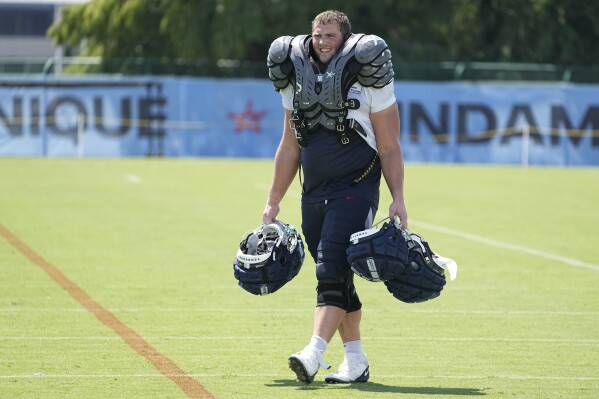 Tennessee Titans rookie offensive lineman Peter Skoronski carries helmets and shoulder pads belonging to veteran players after an NFL football training camp practice Monday, July 31, 2023, in Nashville, Tenn. (AP Photo/George Walker IV)