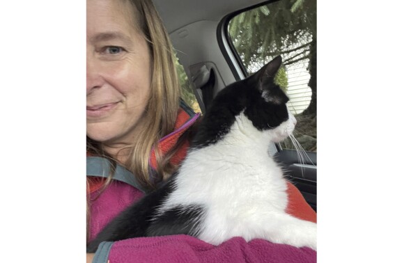 In this photo provided by Elizabeth Wilkins, she is shown with her cat Leo on Aug. 3, 2023, in Juneau, Alaska. Wilkins and her partner Tom Schwartz, were reunited with Leo 26 days after their home collapsed into the swollen Mendenhall River Aug. 5, 2023, in Juneau, Alaska. (Elizabeth Wilkins via AP)