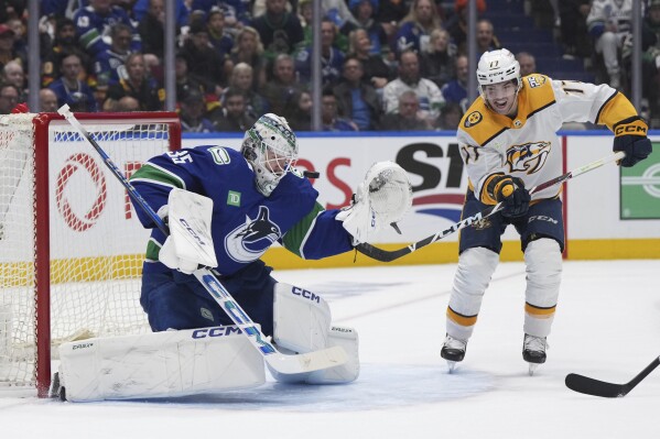Nashville Predators right wing Luke Evangelista (77) looks for a rebound as Vancouver Canucks goaltender Thatcher Demko (35) makes a save during the third period in Game 1 of an NHL hockey Stanley Cup first-round playoff series in Vancouver, British Columbia, on Sunday, April 21, 2024. (Darryl Dyck/The Canadian Press via AP)