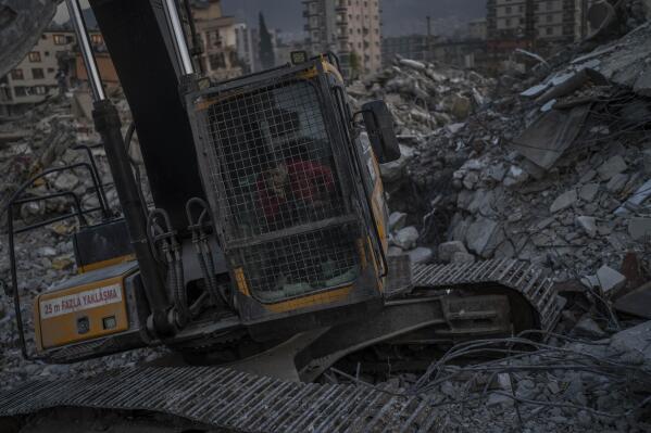 An excavator driver waits for a rescue team to recover the body of an earthquake victim from a collapsed building in Antakya, southeastern Turkey, Sunday, February 12, 2023. Six days after earthquakes killed tens of thousands in Syria and Turkey, sorrow and disbelief are turning to anger and tension. Many in Turkey have a sense that there has been an ineffective, unfair and disproportionate response to the historic disaster. (AP Photo/Bernat Armangue)