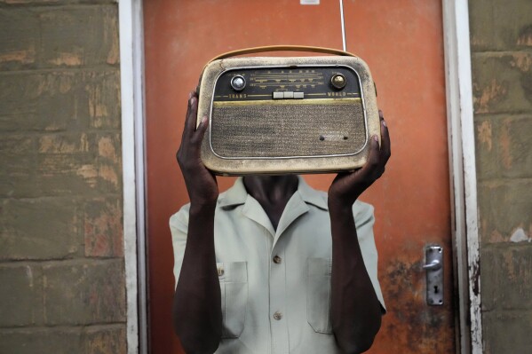 Ngwiza Khumbulani Moyo, a vintage collector holds an old radio set outside his home in Bulawayo, Wednesday, Feb. 15, 2023. According to a survey by Afrobarometer, radio is "overwhelmingly" the most common source of news in Africa. About 68% of respondents said they tune in at least a few times a week, compared to about 40% who said they use social media and the internet. (AP Photo/Tsvangirayi Mukwazhi)