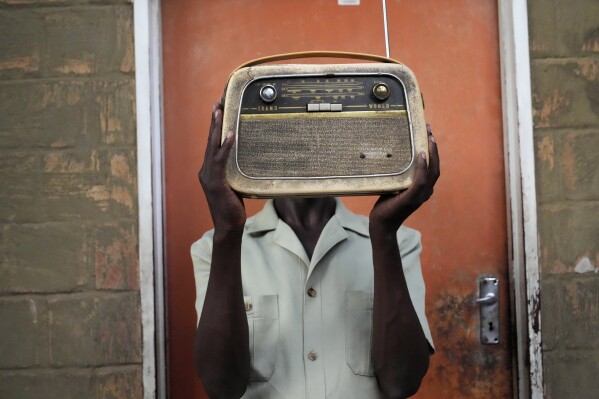 Ngwiza Khumbulani Moyo, a vintage collector holds an old radio set outside his home in Bulawayo, Wednesday, Feb. 15, 2023. According to a survey by Afrobarometer, radio is 