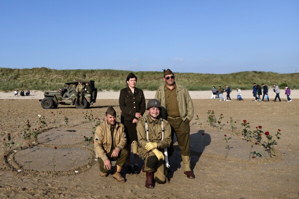 Acteurs poseren voor een foto tijdens een ceremonie op Utah Beach nabij Saint-Martin-de-Varreville, Normandië, donderdag 6 juni 2024. Veteranen uit de Tweede Wereldoorlog uit de hele Verenigde Staten, Groot-Brittannië en Canada zijn deze week in Normandië om markeer de 80ste verjaardag van de landingen in Normandië die hielpen Hitler te verslaan.  (AP Foto/Jeremias Gonzalez)