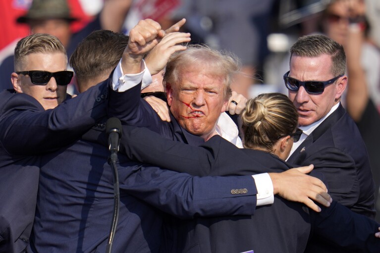 Republican presidential candidate former President Donald Trump pumps his fist as he is helped off the stage at a campaign event in Butler, Pa., on Saturday, July 13, 2024. (AP Photo/Gene J. Puskar)