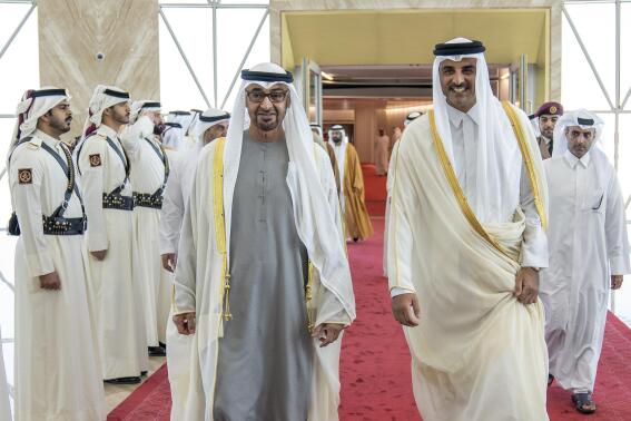 In this photo released by Qatar Amiri Diwan, Qatari Emir Sheikh Tamim bin Hamad Al-Thani, right, greets UAE president Sheikh Mohamed bin Zayed Al Nahyan, upon his arrival at the Hamad International Airport in Doha, Qatar, Monday, Dec. 5, 2022. (Qatar Amiri Diwan via AP)