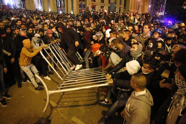 Anti-government protesters remove the fences that was divided between them and the riot police, during a protest near the parliament square, in downtown Beirut, Lebanon, Sunday, Dec. 15, 2019. Lebanese security forces fired tear gas, rubber bullets and water cannons Sunday to disperse hundreds of protesters for a second straight day, ending what started as a peaceful rally in defiance of the toughest crackdown on anti-government demonstrations in two months. (AP Photo/Hussein Malla)