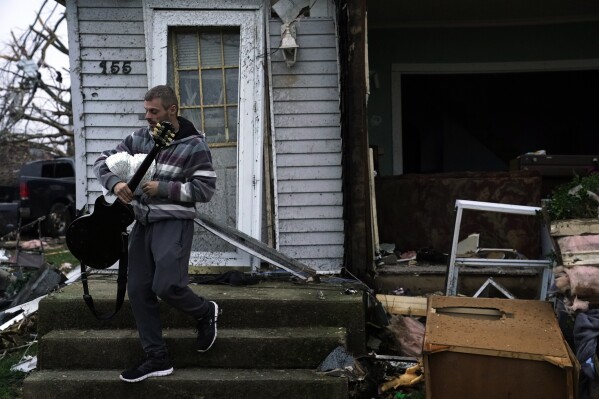 Blaine Schmidt holds his guitar near his damaged home following a severe storm Friday, March 15, 2024, in Lakeview, Ohio. (AP Photo/Joshua A. Bickel)