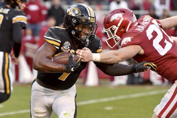 Missouri running back Tyler Badie (1) tries to shake Arkansas defensive back Hayden Henry (27) during the second half of an NCAA college football game Friday, Nov. 26, 2021, in Fayetteville, Ark. (AP Photo/Michael Woods)