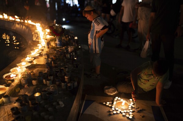 A boy lights candles in the form of the Star of David in honor of victims of the Hamas attacks during a vigil at the Dizengoff square in central Tel Aviv, Israel, Wednesday, Oct 18, 2023. (AP Photo/Petros Giannakouris)