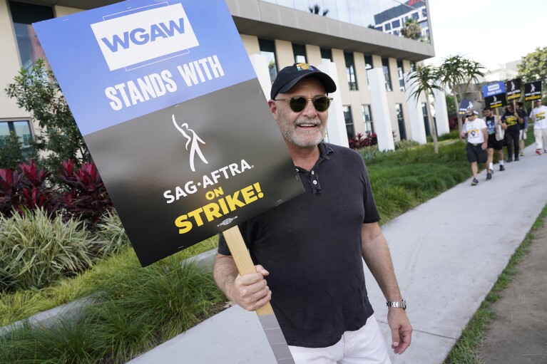 Writer Matthew Weiner carries a sign on the picket line outside Netflix on Wednesday, Sept. 27, 2023, in Los Angeles. Hollywood's writers strike was declared over Tuesday night when board members from their union approved a contract agreement with studios, bringing the industry at least partly back from a historic halt in production. The actors strike continues in their bid to get better pay and working conditions. (AP Photo/Chris Pizzello)