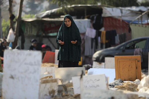 Palestinians visit the graves of people killed in the Israeli bombardment of the Gaza Strip and buried inside the Shifa Hospital grounds in Gaza City, Sunday, Dec. 31, 2023. (AP Photo/Mohammed Hajjar)