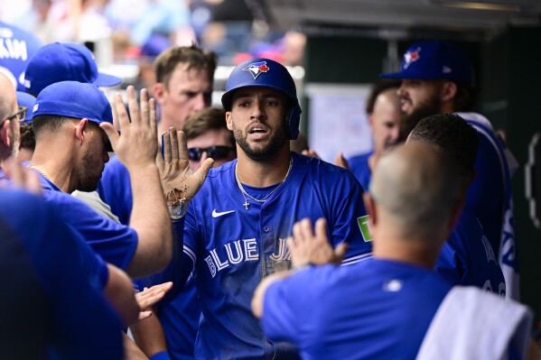 Toronto Blue Jays' George Springer, center, high fives teammates after scoring during the third inning of a baseball game against the Philadelphia Phillies, Wednesday, May 8, 2024, in Philadelphia. (AP Photo/Derik Hamilton)