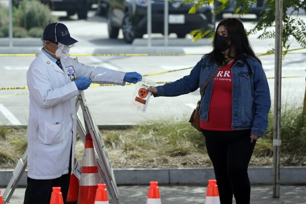 A technician distributes a test kit at a COVID-19 walk-up testing site on the Martin Luther King Jr. Medical Campus Thursday, Jan. 7, 2021, in Los Angeles. (AP Photo/Marcio Jose Sanchez)
