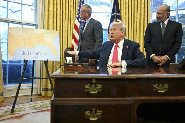 President Donald Trump gestures to a poster that says "Gulf of America" as Health and Human Services Secretary Robert F. Kennedy Jr., left, and Commerce Secretary Howard Lutnick watch in the Oval Office at the White House in Washington, Feb. 25, 2025. (Pool via AP, file)