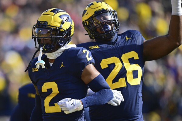 Michigan defensive back Will Johnson, left, celebrates with defensive lineman Rayshaun Benny after intercepting a pass during the first half of an NCAA college football game against Ohio State, Saturday, Nov. 25, 2023, in Ann Arbor, Michigan. (AP Photo/David Dermer)