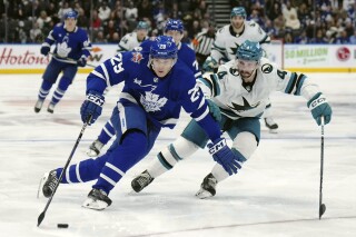 Toronto Maple Leafs forward Pontus Holmberg (29) protects the puck from San Jose Sharks defenseman Kyle Burroughs (4) during the second period of an NHL hockey game, Tuesday, Jan. 9, 2024 in Toronto. (Nathan Denette/The Canadian Press via AP)