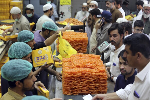 FILE - People buy sweets at a shop in preparation for the upcoming Eid al-Fitr celebrations, in Peshawar, Pakistan, Sunday, May 1, 2022. (AP Photo/Mohammad Sajjad, File)