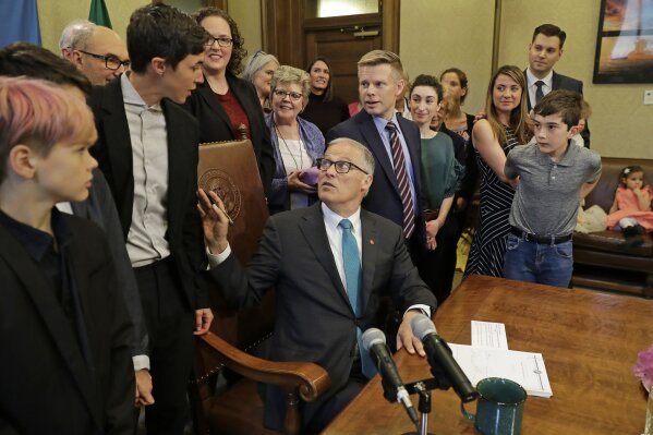 
              Washington Gov. Jay Inslee, center, turns to talk with Katrina Spade, upper left, the founder and CEO of Recompose, a company that hopes to use composting as an alternative to burying or cremating human remains, Tuesday, May 21, 2019, at the Capitol in Olympia, Wash., before signing a bill into law that allows licensed facilities to offer "natural organic reduction," which turns a body, mixed with substances such as wood chips and straw, into soil in a span of several weeks. The law makes Washington the first state in the U.S. to approve composting as an alternative to burying or cremating human remains. (AP Photo/Ted S. Warren)
            