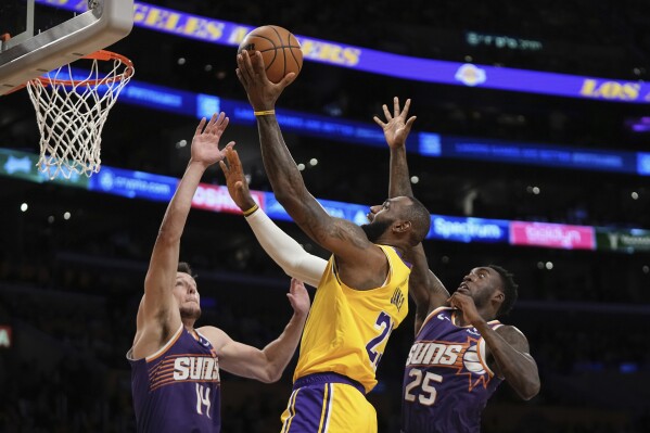 Los Angeles Lakers forward LeBron James, center, shoots as against the Phoenix Suna center Drew Eubanks, left, and forward Nassir Little defend during the first half of an NBA basketball game Thursday, Oct. 26, 2023, in Los Angeles. (AP Photo/Mark J. Terrill)