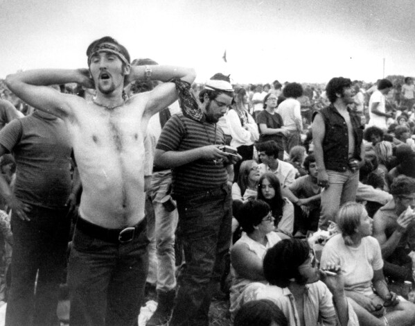 FILE - Music fans relax during a break in the entertainment at the Woodstock Music and Arts Fair, Aug. 16, 1969, in Bethel, N.Y. An estimated 450,000 people attended the Woodstock festival in August 1969, and most of that crowd was composed of teenagers or young adults now in the twilight of their lives. That ticking clock is why the Museum at Bethel Woods, based at the site of the festival, is immersed in a five-year project traveling around the United States recording the oral histories of people were there, preserving the Woodstock memories before they fade away. (AP Photo, File)