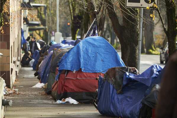 FILE - Tents line the sidewalk on SW Clay St in Portland, Ore., Dec. 9, 2020. According to an annual report released by regional officials Wednesday, Dec. 20, 2023, fentanyl and methamphetamine drove a record number of homeless deaths last year in Oregon's Multnomah County, home to Portland. (AP Photo/Craig Mitchelldyer, File)