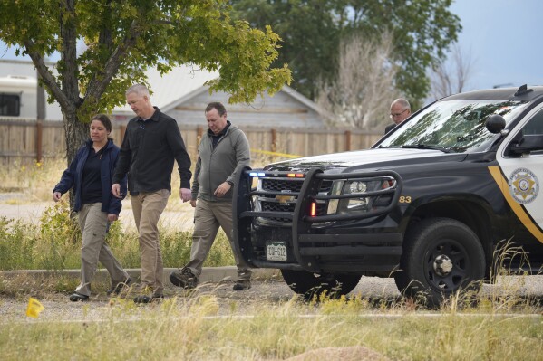 Authorities walk outside a closed funeral home where 115 bodies have been stored, Friday, Oct. 6, 2023, in Penrose, Colo. Authorities are investigating the improper storage of human remains at the southern Colorado funeral home that performs "green" burials without embalming chemicals or metal caskets. (AP Photo/David Zalubowski)