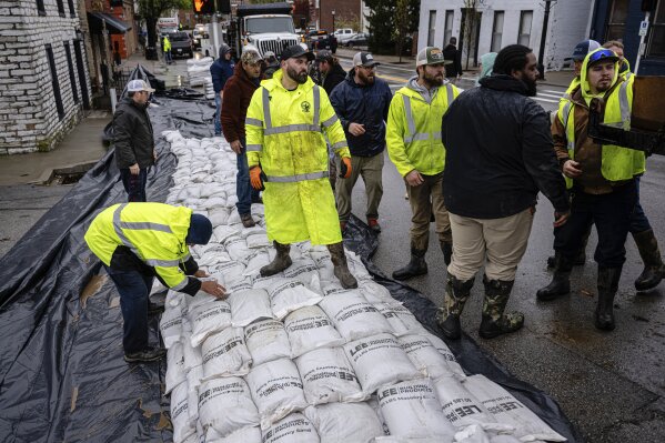 City workers and volunteers stack sandbags in preparation of rising floodwaters on Sunday, April 6, 2025, in Frankfort, Ky. (AP Photo/Jon Cherry)