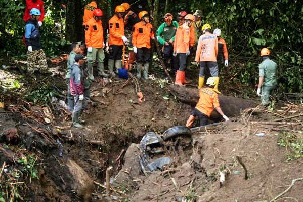 I soccorritori cercano le vittime dopo che una frana provocata dalla pioggia ha travolto le auto in transito su una strada a Mojokerto, Giava orientale, Indonesia, venerdì 4 aprile 2025. (AP Photo)