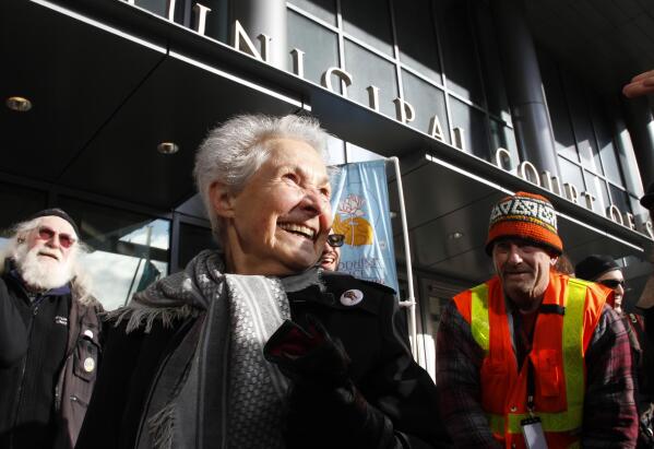 FILE - Dorli Rainey, 84, center, who was pepper-sprayed by police while taking part in an "Occupy Seattle" protest, smiles before speaking on Nov. 18, 2011, in front of police headquarters in downtown Seattle. Rainey, who became a symbol of the Occupy protest movement after she was pepper-sprayed by Seattle police in 2011, has died on Aug. 12, 2022, at age 95. Her daughter, Gabriele Rainey, said her mom was “so active because she loved this country, and she wanted to make sure that the country was good to its people.” (AP Photo/Ted S. Warren, File)