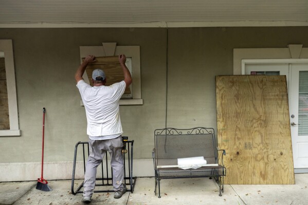 Tybee Island, Ga., resident Bryan Moore helps his friend board up his house on the island, Tuesday, Aug. 29, 2023, ahead of Hurricane Idalia. Forecasters at the National Hurricane Center in Miami said Idalia is expected to become a major hurricane Tuesday night before it reaches the Big Bend — where the Florida Panhandle curves into the peninsula — and is still likely to be a hurricane while moving across southern Georgia on Wednesday, Aug. 30. (Stephen B. Morton/Atlanta Journal-Constitution via AP)