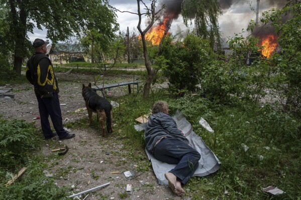 A man lies on the ground as he watches his burning house destroyed by a Russian airstrike in Vovchansk, Ukraine, on Saturday, May 11, 2024. (Ǻ Photo/Evgeniy Maloletka)