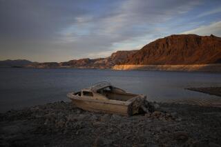 FILE - A formerly sunken boat sits high and dry along the shoreline of Lake Mead at the Lake Mead National Recreation Area, on May 10, 2022, near Boulder City, Nev. More human remains found last summer at drought-stricken Lake Mead have been identified as a Las Vegas man missing since July 1998. (AP Photo/John Locher, File)