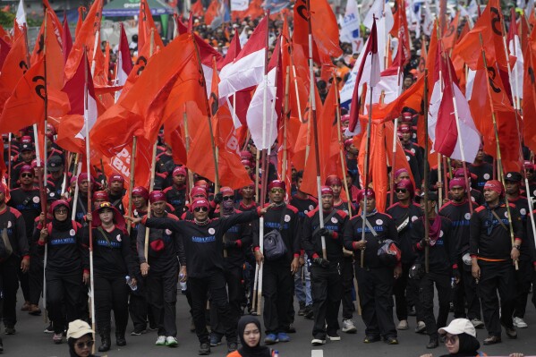 Arbeiders marcheren tijdens een 1 mei-parade in Jakarta, Indonesië, woensdag 1 mei 2024. Duizenden arbeiders drongen er bij de regering op aan het minimumloon te verhogen en de arbeidsomstandigheden te verbeteren.  (AP Foto/Ahmed Ibrahim)