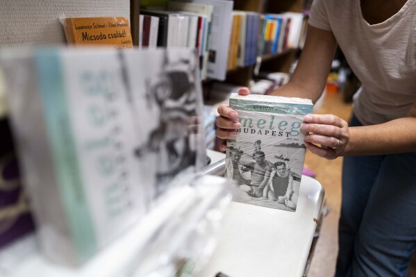 An employee of a bookstore wraps a book featuring LGBTQ+ content in closed packaging to comply with a contentious law on homosexuality in media, on Wednesday, July 26, 2023 in Budapest, Hungary. Booksellers in Hungary must decide whether to comply with a law requiring books that depict homosexuality to be placed in closed packaging on their shelves. Some bookstores have already received hefty fines from the right-wing government for failing to do so, while others have opted to abide by the legislation, despite their opposition to it. (AP Photo/Bela Szandelszky)