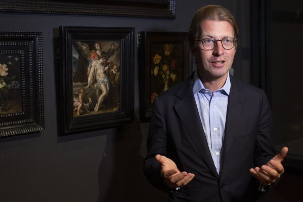 Rijksmuseum director Taco Dibbits, standing in front of Bartholomeus Spanger's "Body of Christ Supported by Angels" oil on copper painting, left, discusses the gift of the major painting the cultural institution received to underscore support for the victims of the coronavirus pandemic and the crisis that museums face world wide, which went on display in Amsterdam, Netherlands, Monday, June 1, 2020. The Dutch government took a major step to relax the coronavirus lockdown, with bars, restaurants, cinemas and museums reopening under strict conditions. (AP Photo/Peter Dejong)