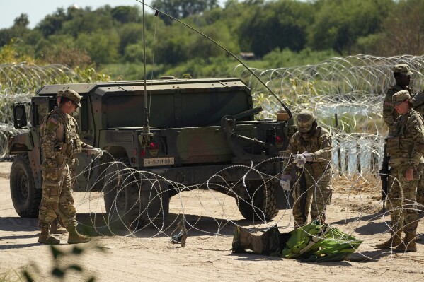 Miembros de las fuerzas de seguridad instalan un alambre con concertinas en una zona utilizada por migrantes para cruzar el Río Bravo desde México a Estados Unidos, el 21 de septiembre de 2023, en Eagle Pass, Texas. (AP Foto/Eric Gay)