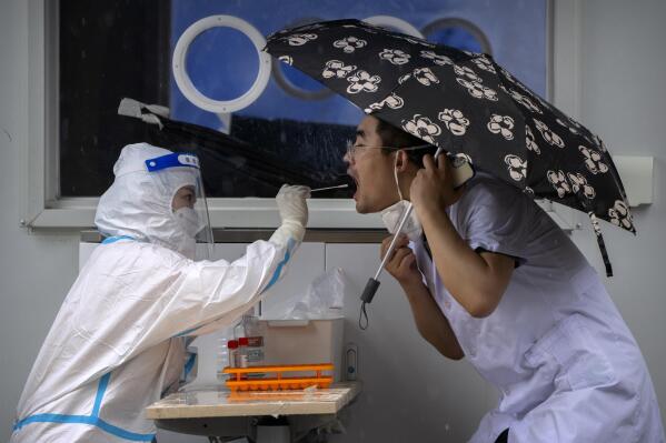 FILE - A worker wearing a protective suit swabs a man's throat for a COVID-19 test at a coronavirus testing site in Beijing, on June 22, 2022. The World Health Organization said Friday May 5, 2023 that COVID-19 no longer qualifies as a global emergency, marking a symbolic end to the devastating coronavirus pandemic that triggered once-unthinkable lockdowns, upended economies and killed millions of people worldwide. (AP Photo/Mark Schiefelbein, File)