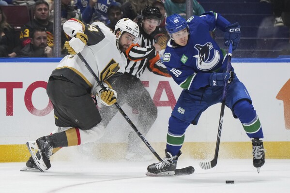 Vancouver Canucks' Andrei Kuzmenko, right, takes the puck from Vegas Golden Knights' Nicolas Hague during the first period of an NHL hockey game Thursday, Nov 30, 2023, in Vancouver, British Columbia. (Darryl Dyck/The Canadian Press via AP)