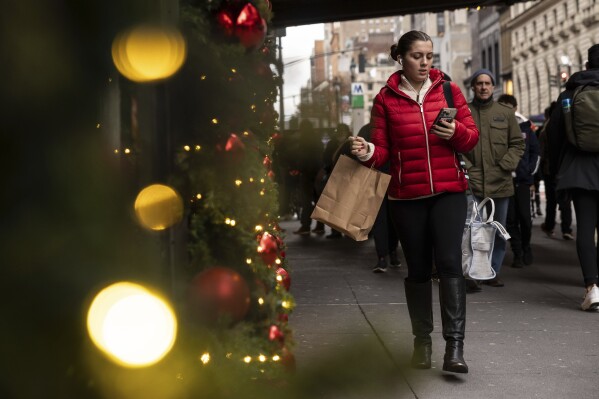 A woman carrying a shopping bag passes Macy's department store in Herald Square, Monday, Dec. 11, 2023, in New York. On Thursday, the Commerce Department releases U.S. retail sales data for November. (AP Photo/Yuki Iwamura)