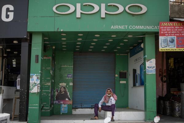 FILE- A man speaks on his mobile phone in front of a shop selling Oppo phones in Noida, outskirts of New Delhi, India, Thursday, June 18, 2020. Indian investigators have raided an Indian subsidiary of Chinese smartphone maker Oppo, accusing it of evading customs duties totaling 43.9 billion rupees ($551 million), the government said Wednesday. (AP Photo/Altaf Qadri)