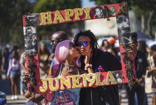 Daisa Chantel kisses Anthony Beltran as they take a picture to celebrate Juneteenth at Leimert Park in Los Angeles on Saturday, June 18, 2022. (AP Photo/Damian Dovarganes)