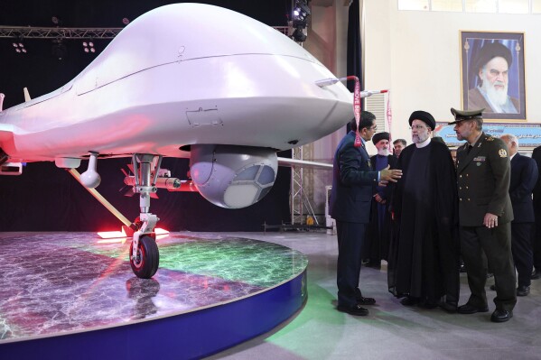 In this photo released by the Iranian Presidency Office, President Ebrahim Raisi, second right, listens to Chief of Aviation Industries of Armed Forces Gen. Afshin Khajehfard, as Defense Minister Gen. Mohammad Reza Gharaei Ashtiani, right, listens, during a ceremony unveiling a drone called the Mohajer-10, Tuesday, Aug. 22, 2023. Iran's Defense Ministry unveiled a drone Tuesday resembling America's armed MQ-9 Reaper, claiming that the aircraft capable of staying airborne for 24 hours and having the range to reach its archenemy Israel. (Iranian Presidency Office, via AP)
